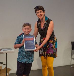 Young child receiving an award for best entry in a science writing competition
